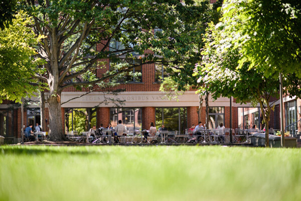 People seated at tables in front of the Penn Law building in the courtyard on a sunny day.