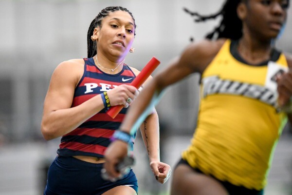 During a race, Isabella Whittaker runs with a baton in her hand, trailing a runner from Towson.