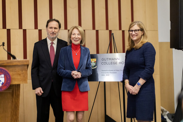 Doyle, Gutmann, Magill on stage with sign that reads "Gutmann College House"