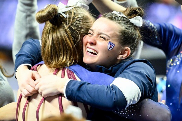 Two members of the gymnastics team hug in celebration.