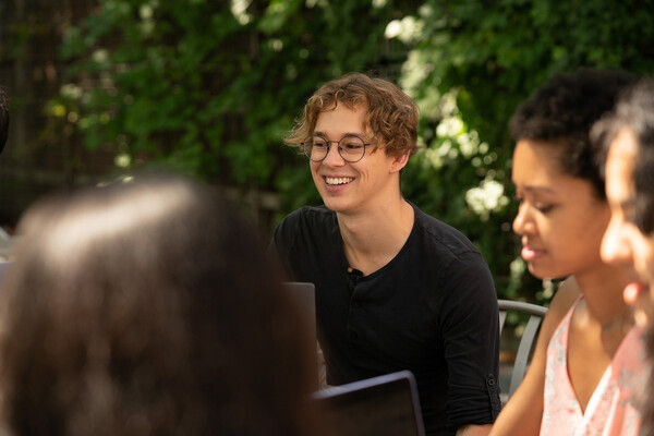 Tom Etienne with students sitting outside.