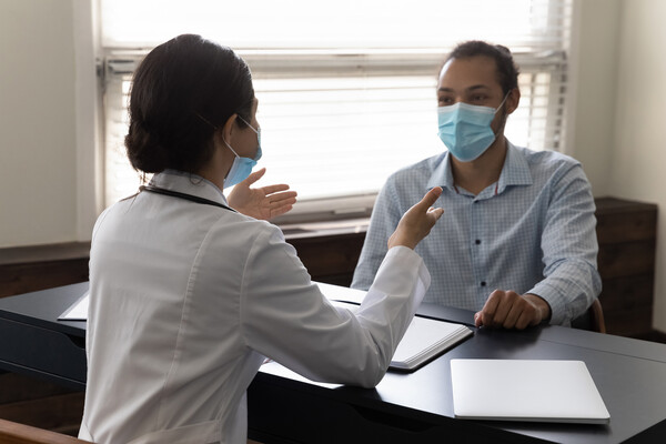 Patient sitting at a desk speaking with a doctor.