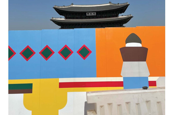 A painted wall in front of a traditional Korean building.