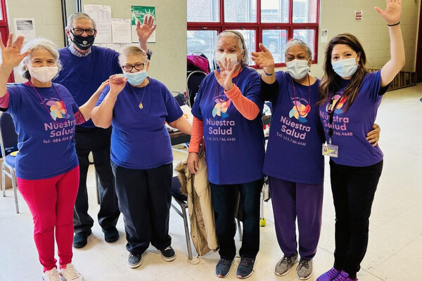 Four older Latinx people with Ruby Rivera and Adriana Perez at a community health center. 