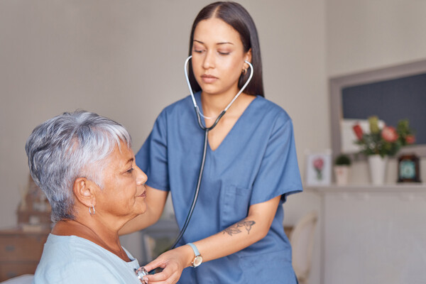 A home health worker checks the heartbeat of a senior patient.