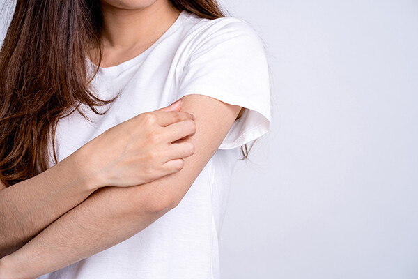 person scratching their arm with their other hand