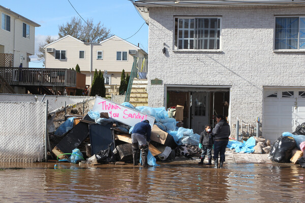People clean up a house damaged by a hurricane.