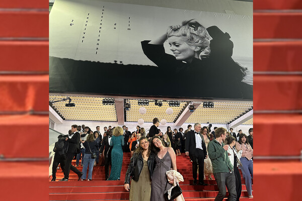 two students standing on the red carpet steps with many people behind them