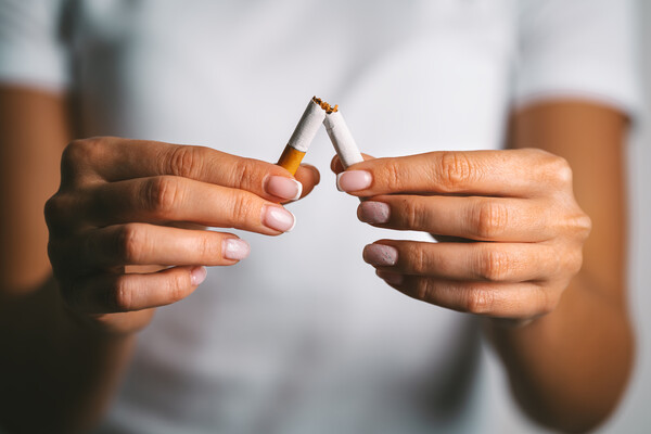 Person breaking a cigarette in half.
