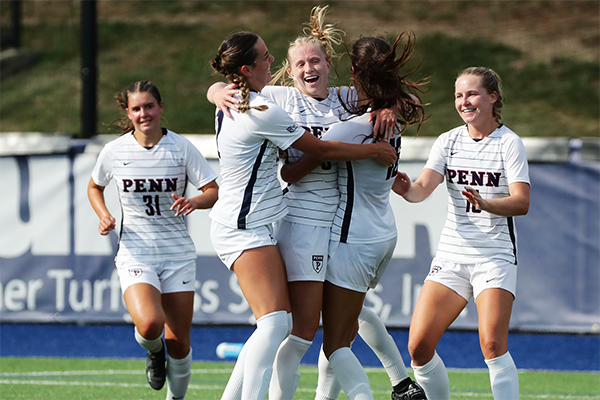 Players on the women's soccer team hug and celebrate after a big moment during a game.