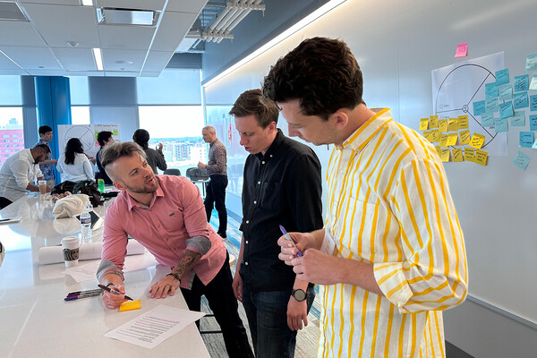 Three people discussing a document at a table at a conference.