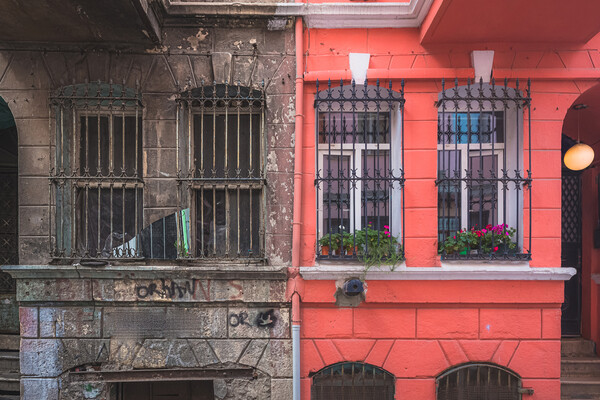 Run-down residence next to painted residence with flowers.