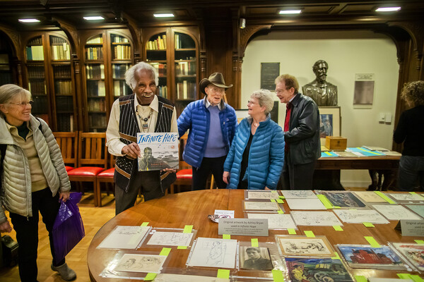 Ashley Bryan holds up one of his books from a table in Penn’s Kislak Center.