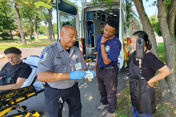 Four people, one on a stretcher, outside an ambulance learning how to administer Narcan.