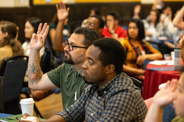 postdocs sitting at tables, raising hands
