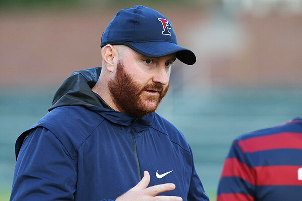 Brian Gill speaks with a player on the sidelines during a game.