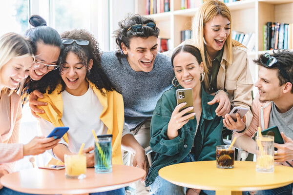Seven college students laughing around tables with cocktails.