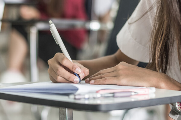 Student holding pencil to paper pamphlet.