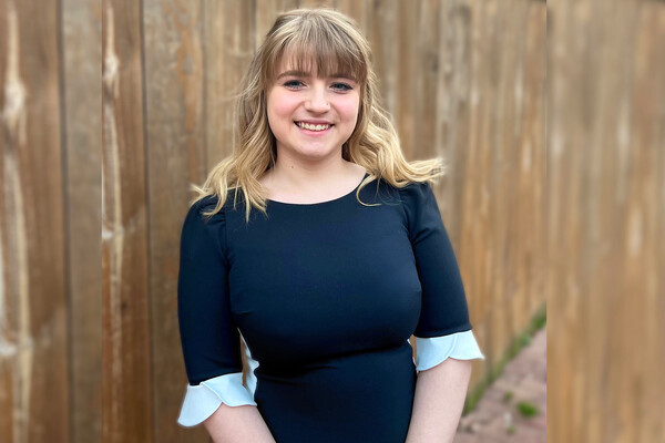Jade Golzalez standing outside with a wooden fence behind her