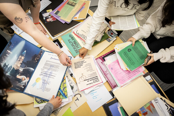 Three students looking at gender, sexuality, and women’s studies archival material.