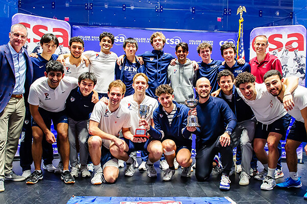 Members of the men's squash team pose with their championship trophy after defeating Trinity.