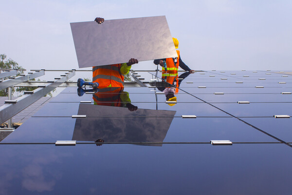 Solar panel workers installing a panel to a roof.