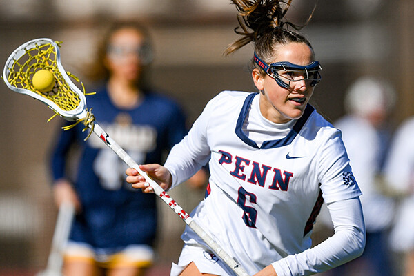 Izzy Rohr runs up the field with her stick in her hands, which contains the ball.