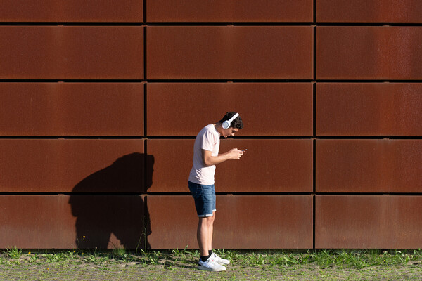 A teenager with headphones slouching over their phone.