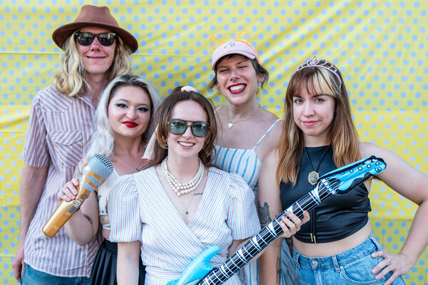 A group of people posing and smiling in front of a polka dot backdrop.