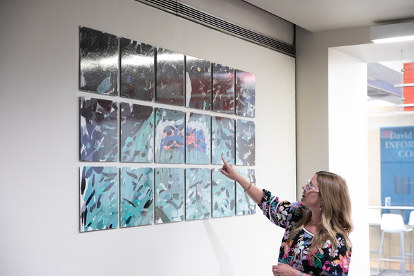 Lynn Dolby points to one of Jennifer Bartlett’s “In the Garden” panels.