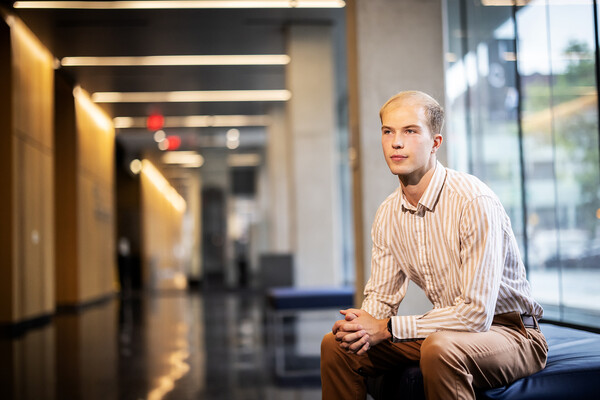Silas Ruth poses on a bench near windows.