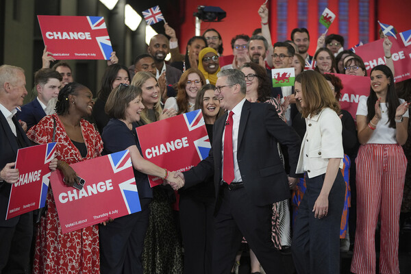 Keir Starmer shakes hands with supporters holding signs that say Change and look like the UK flag.