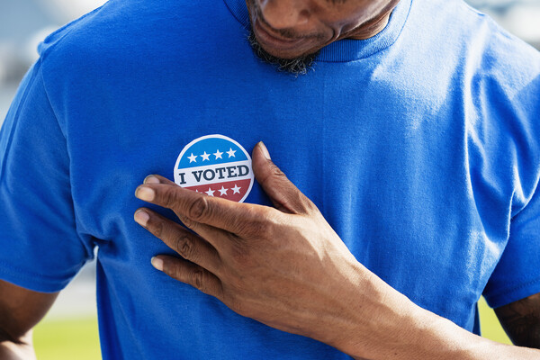 A person affixes an I VOTED sticker to their t-shirt.