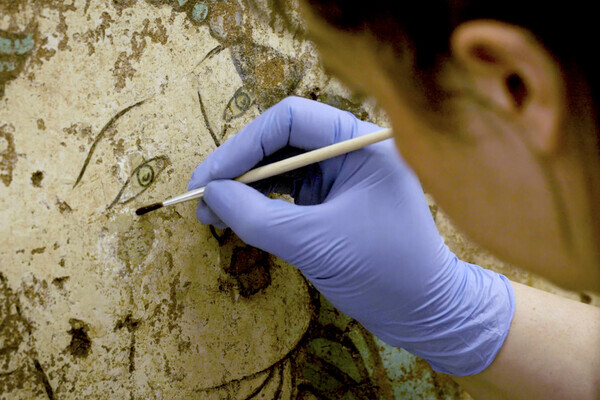 museum worker restoring buddhist mural