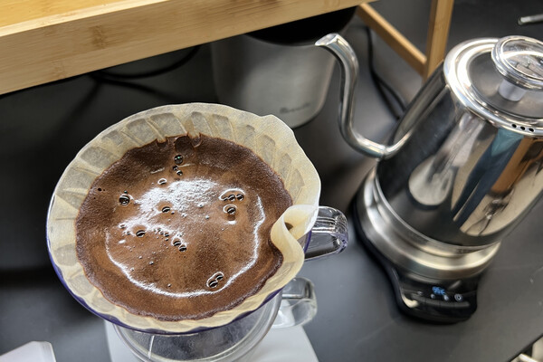 A kettle and pour-over coffee filter full of coffee grounds.