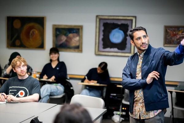 Rahim Ullah stands in front of a class of students speaking. 