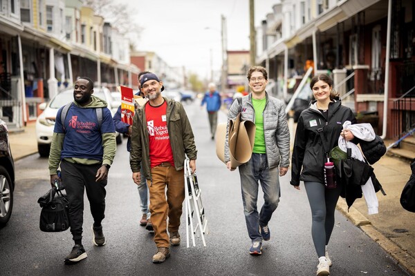 Volunteers smiling and carrying tools and supplies during the block build event.