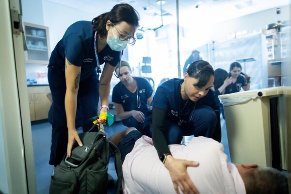 Nursing students help man on floor in disaster simulation.