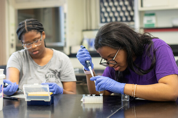 Two high school students woking with pipettes in a science classroom.