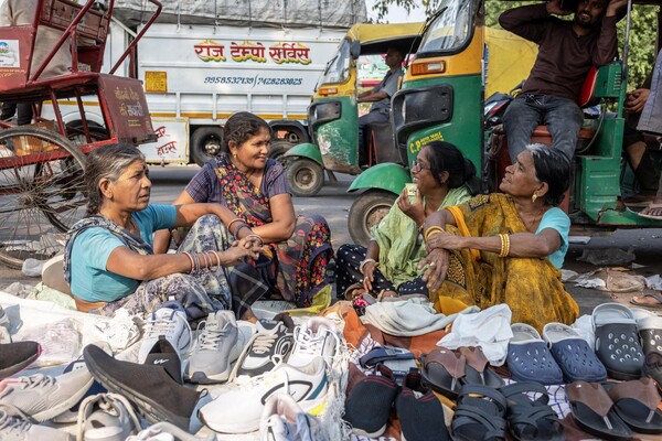 Four women street vendors sell shoes and footwear on a Delhi street.