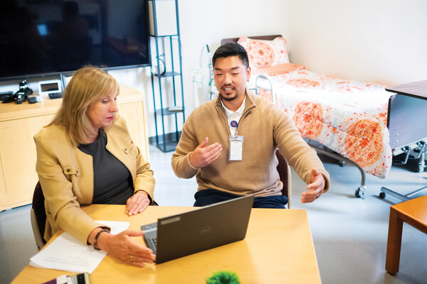 two health professionals in discussion at a laptop