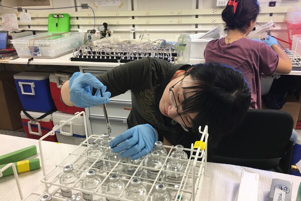 Researcher Xin Sun injects substance into glass vials.