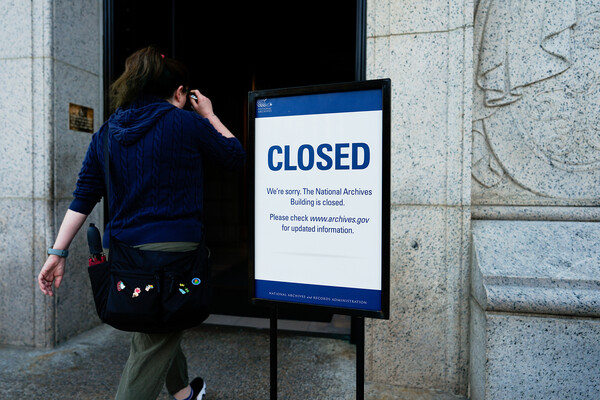 A woman walks by a "closed" sign in front of the National Archives building in Washington, D.C.