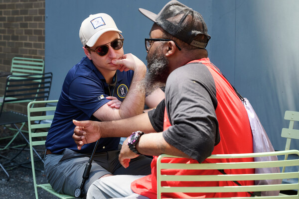 Zachary Kosak talks with Danny at a table outdoors.
