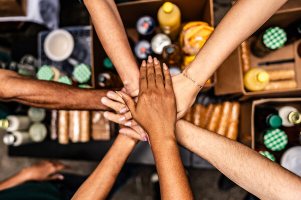 Five people having a group all hands in on three moment.
