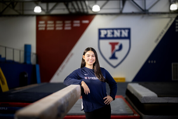 Carly Oniki leans against a balance beam in the gymnastics training center.