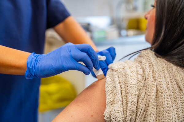 A person getting a bandage on their arm after a flu shot from a medical provider.