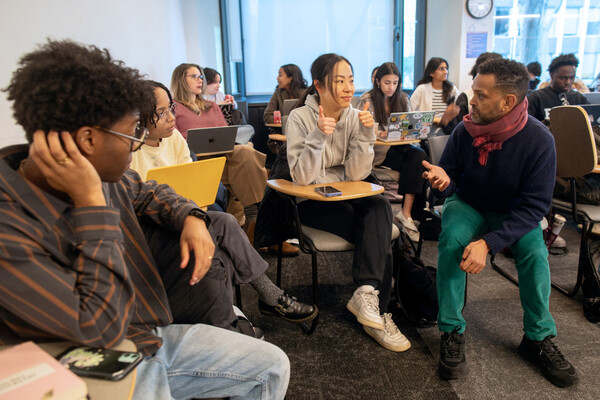 Dag Woubeshet (right) speaks with student in a classroom who is giving the thumbs up.