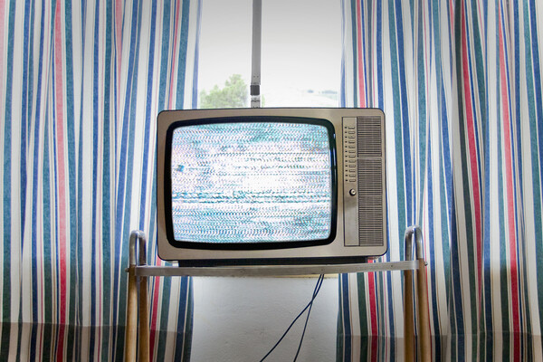 An old television set in front of curtained windows.
