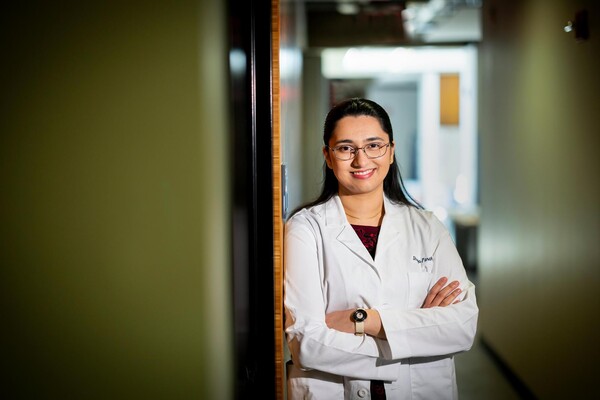 Shreya Parchure in a white coat in the Laboratory for Cognition and Neural Stimulation in the Goddard Laboratory on Penn's campus, smiling with arms crossed and facing forward.